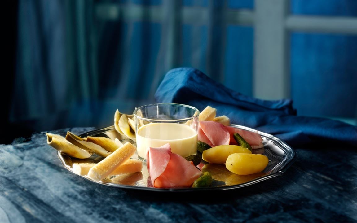 Cheese fondue with artichokes, smoked ham and gherkins