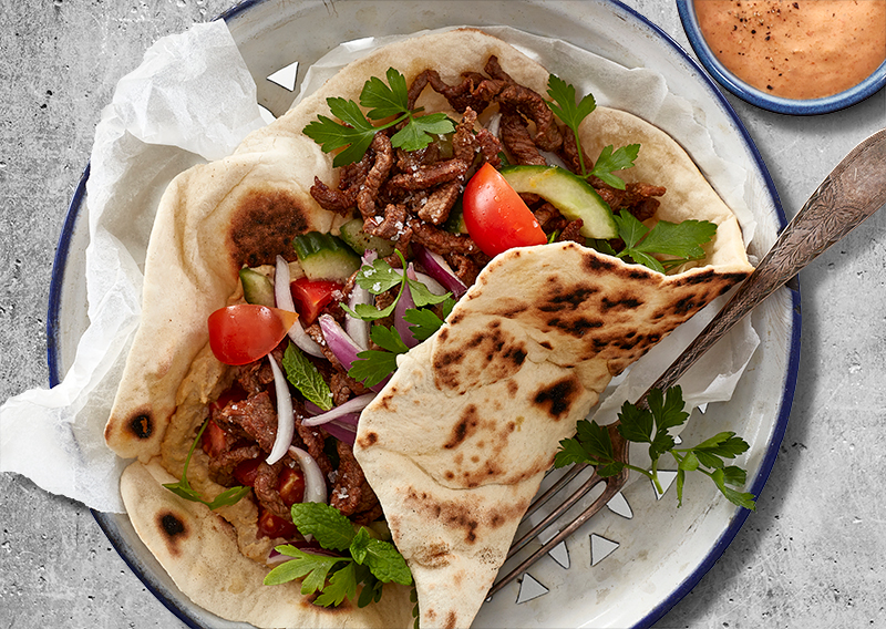 Kebab med fladbrød, hummus, grillet peberfrugtsdressing og friske grøntsager