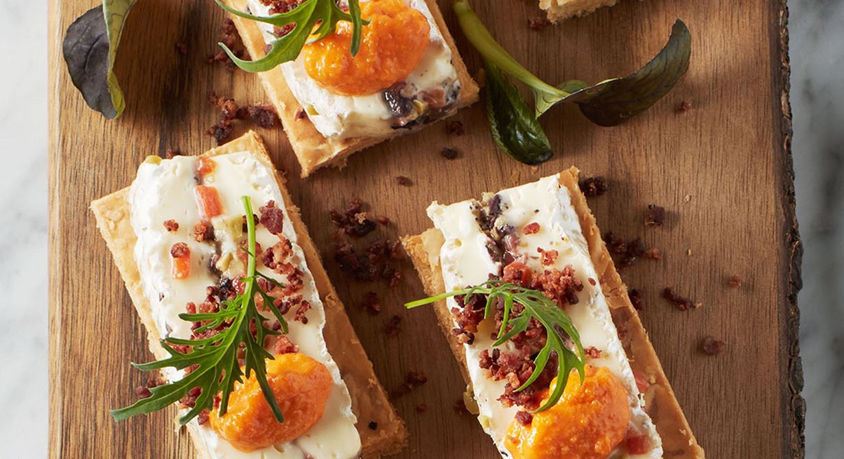 En ost-petit-four med Brie de Meaux på frasig smördeg i smakrikt sällskap av oliver, pimentopuré och rostat sidfläsk. Lätt att förbereda och servera som liten amuse till gästerna.