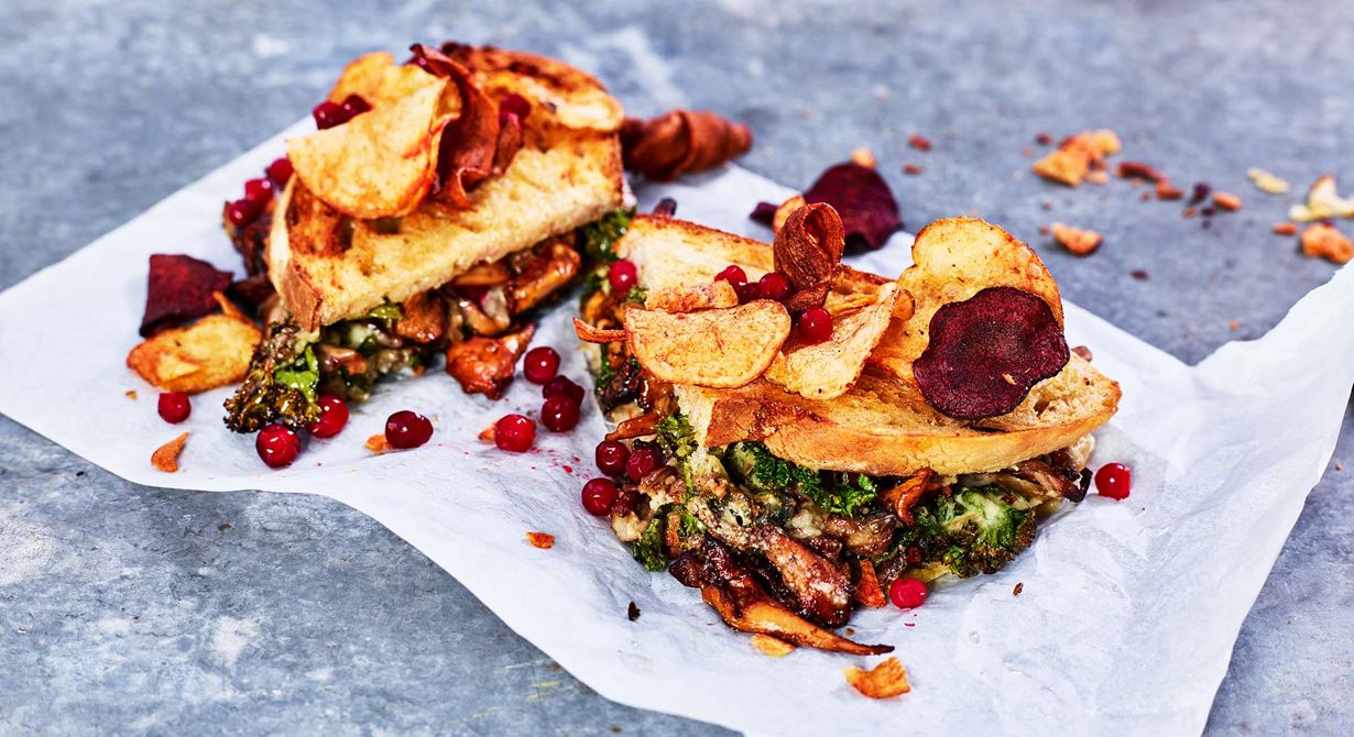 Den grillade mackan fylls med ostkräm, stekt svamp och grönkål. Lingon ger härlig syra, extra ostskivor härlig textur och chipsen som serveras till lite krisp. I säsong används gärna kantareller till denna vegetariska ost- & svampmacka. Utanför säsong fungerar t ex champinjoner och shiitake bra. Grilla tills levainskivorna är krispiga i t ex en Merrychef.