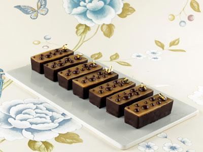 Krämig och len kolafudge på valnötsbotten med chokladprickar och bladguld som ger en modern, lite ostrukturerad dekor.