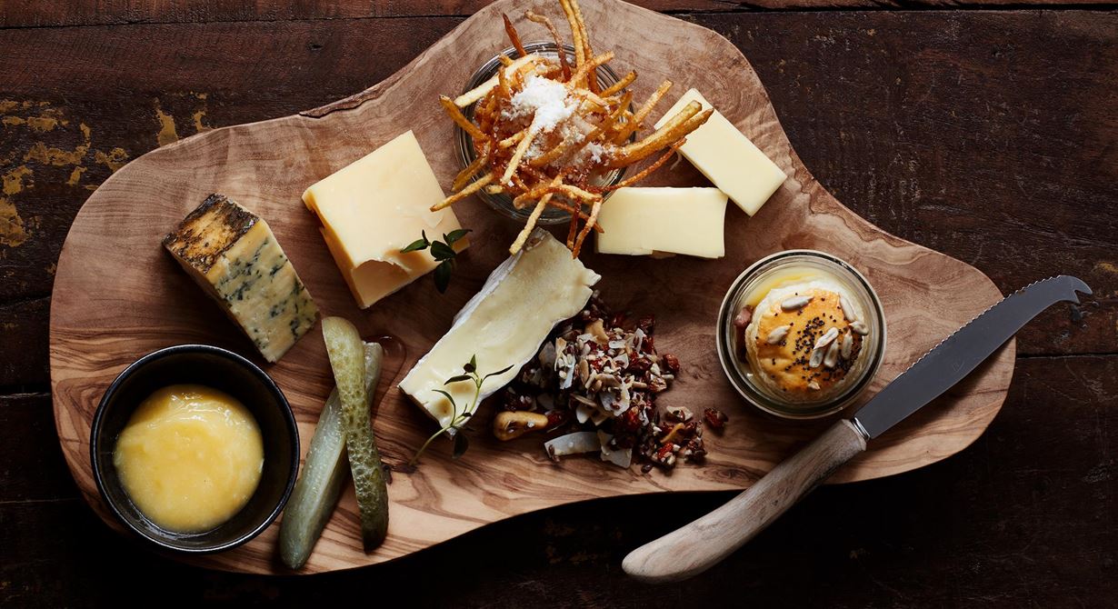 Smält raclette i kopp med lock av smördeg får sällskap av smakrika ostar. Syrad gurka, knaprig parmesanpotatis, lemon curd och en havtornsgranola blir rustika, goda tillbehör. En riktig gourmetostbricka att erbjuda gästerna!