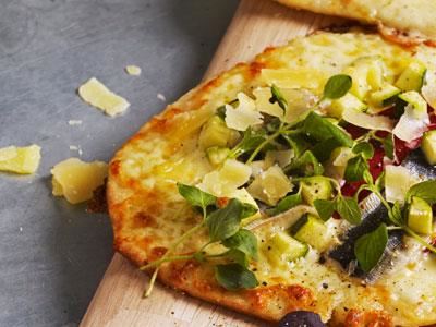 Det här är en pizzetta bianca, vilket betyder liten pizza som är grundad med ost istället för tomatsås. Sedan toppas den med inlagd paprika så kallad pimiento, marinerade sardiner och zucchini. Skär upp som aptitretare eller erbjud pizzettan som en för- eller mellanrätt på menyn.