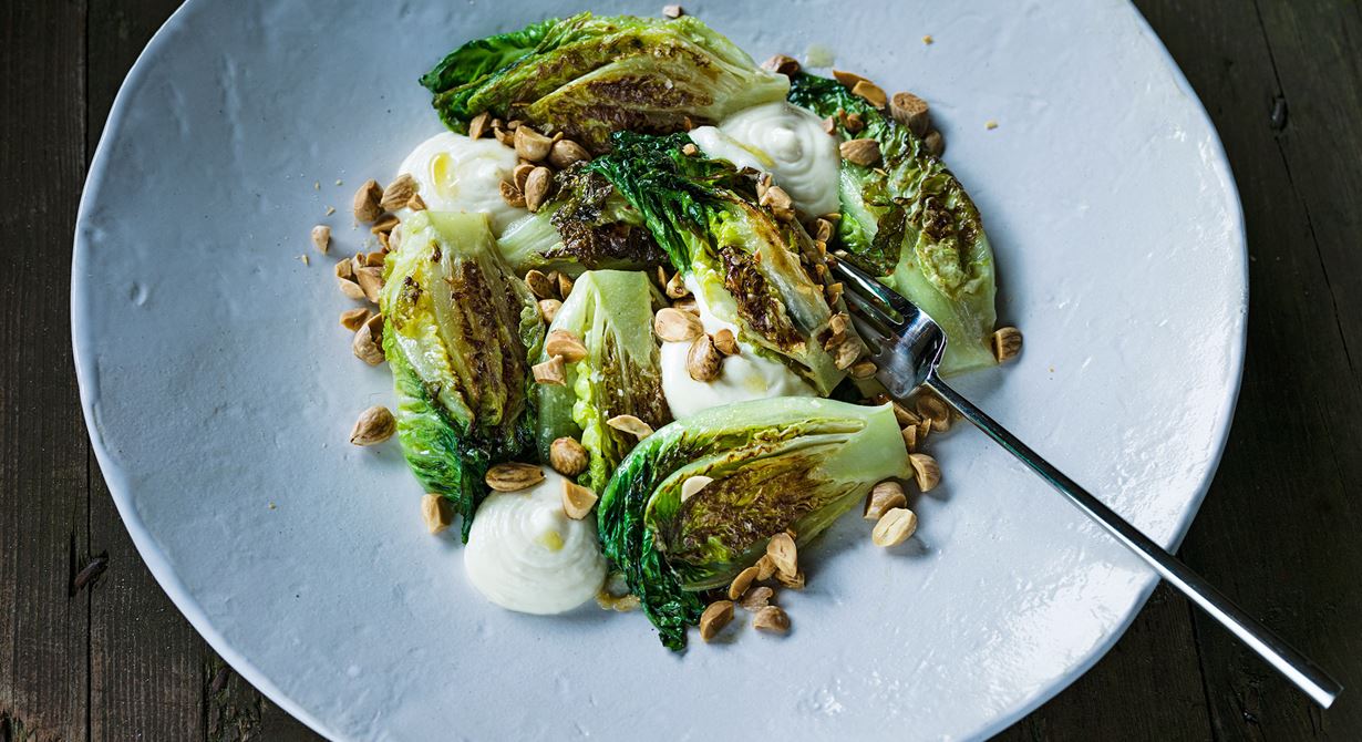 En tillagad sallad med härliga konsistenser av mjukt och knaprigt. Sallad är en perfekt grönsak att smörsteka eftersom den suger åt sig andra smaker så bra. Grymt gott med den aioliliknande vitlöksemulsionen och de rostade mandlarna.