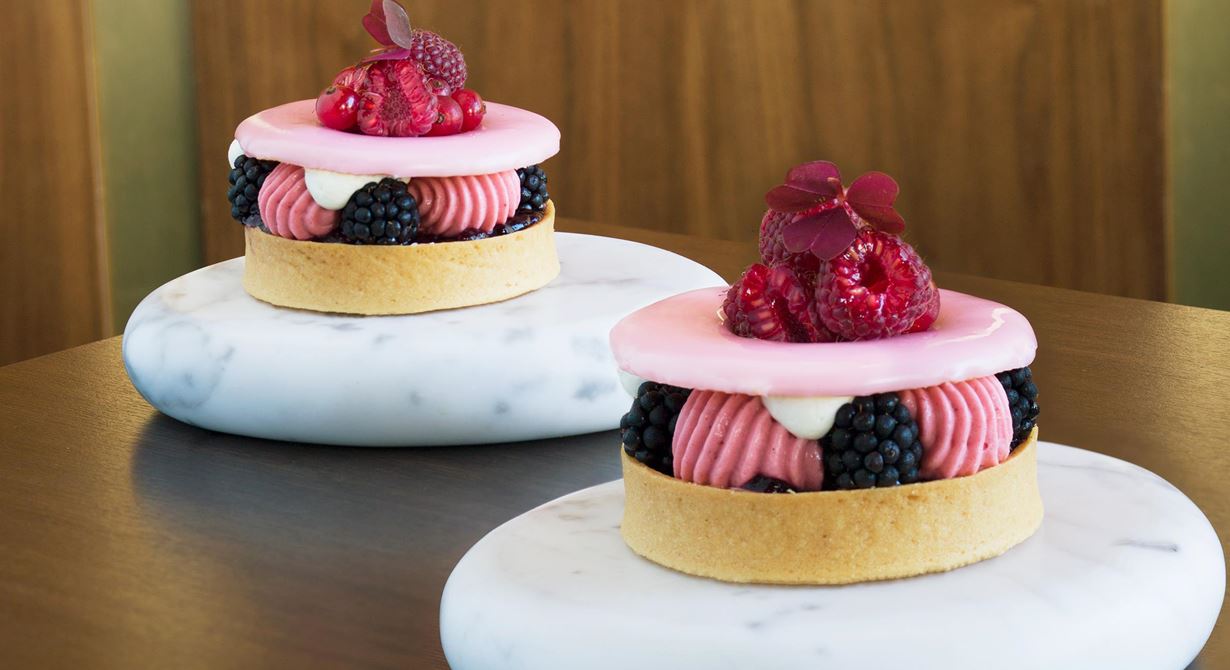 En vacker restaurangdessert på svenska bär. Tartelett på linserdeg fylls med en utsökt bärkompott, luftig pannacotta på röda bär, sval crème fraiche och toppas med blankt glaserat och dekorerat lock.